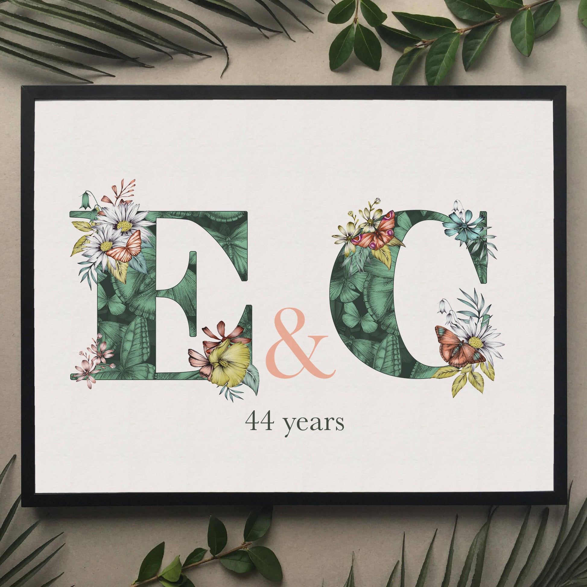 Personalised initial digital print of E & C. Initials are filled with fine liner drawings of butterflies and flowers. Underneath initials ’44 years’ is printed. B. Print is framed and surrounded with green leaves.