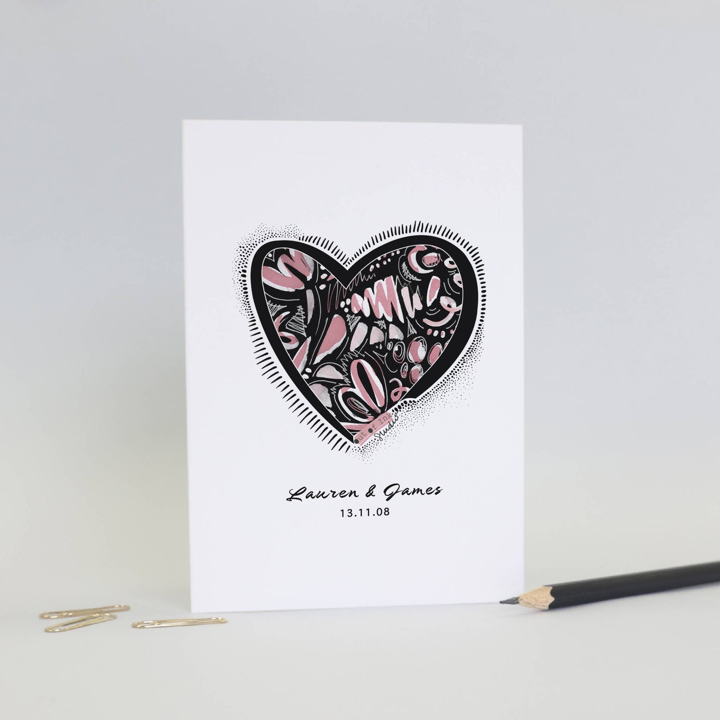 A card with a printed heart on the front  filled with abstract ink doodle in pink. Personalised with the recipients names and a date 