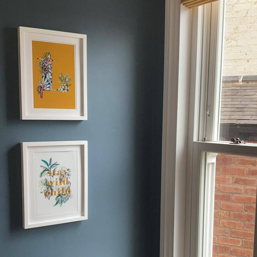 Mustard coloured artwork on a blue wall near window. Stay wild child wording is featured on print.