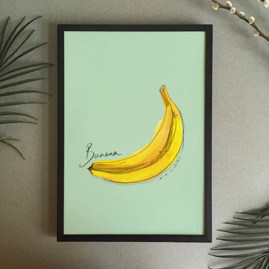 A digital art print with a hand-painted banana on a green background with text ‘banana’ hand written on it.