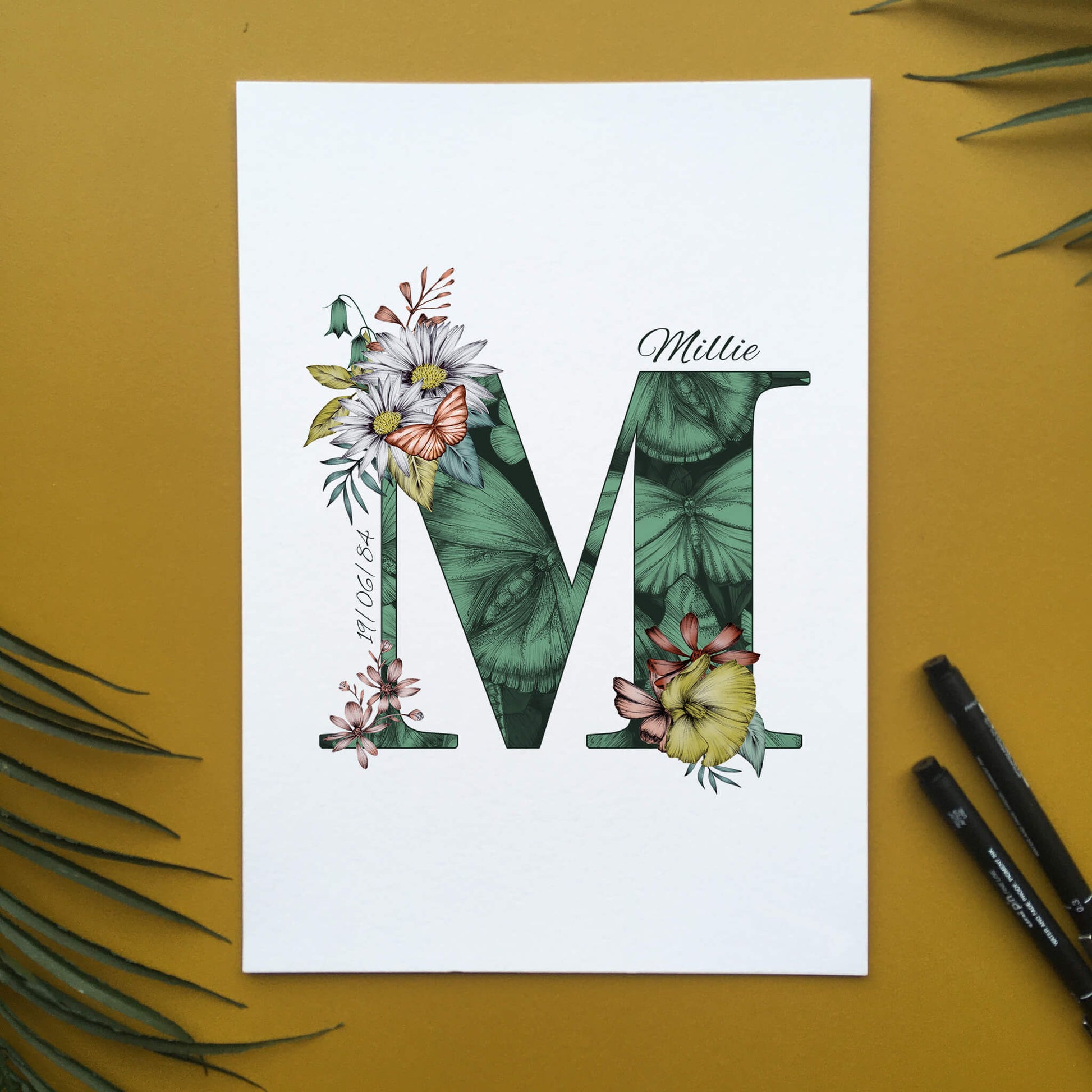 Personalised initial M print is filled with fine liner drawings of butterflies and flowers with a green theme and personalised with the recipients name and date of birth.