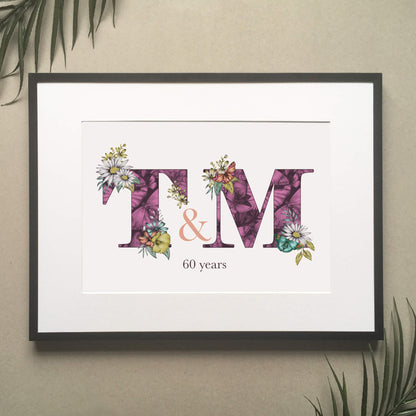 Personalised initial digital print of T & M. Initials are filled with fine liner drawings of butterflies and flowers. Underneath initials ’60 years’ is printed. Print is framed and surrounded with green leaves.