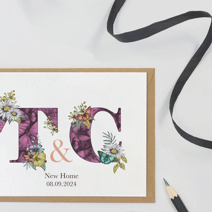 Purple personalised new home card with T & C initials filled with hand-drawn butterflies and flowers. The wording ‘New Home and the moving in date is printed underneath initials.