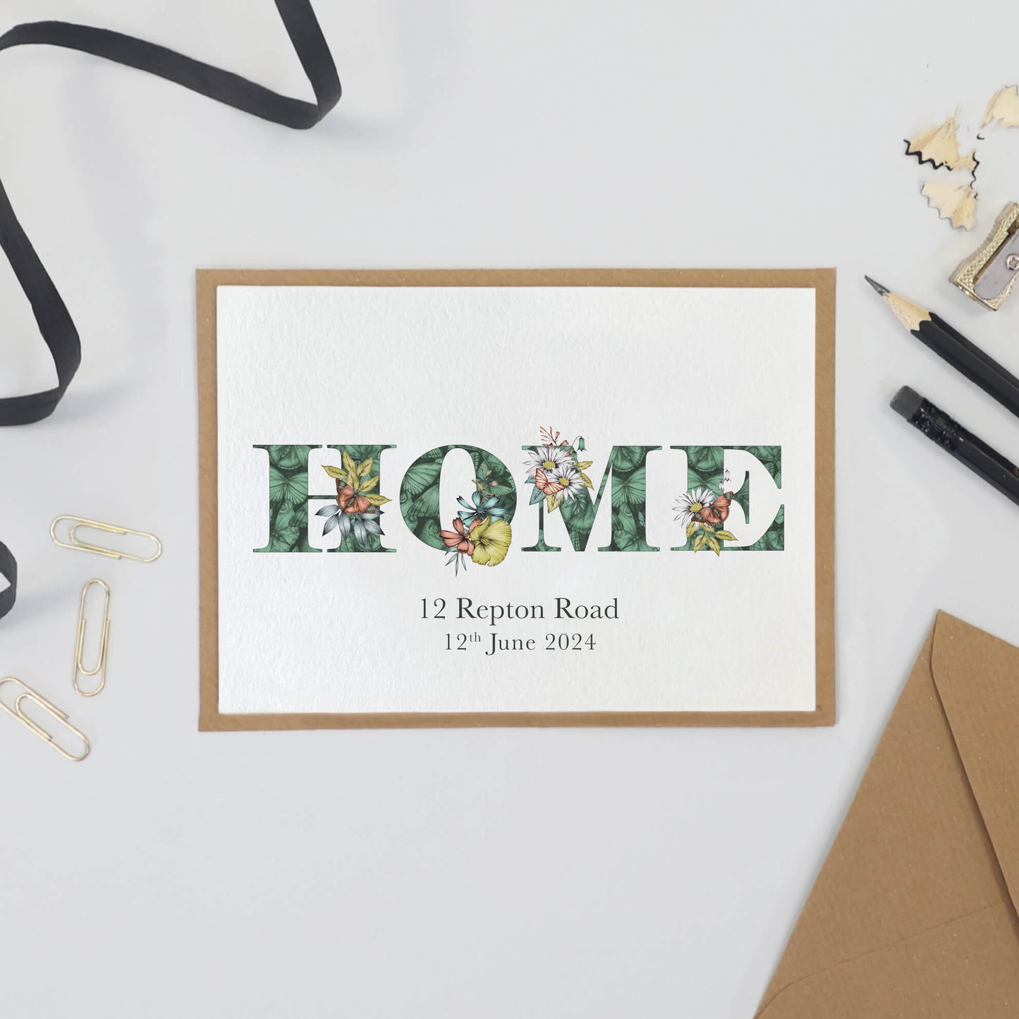 'HOME' printed on a card. Personalised with the first line of their address and moving in date printed underneath.