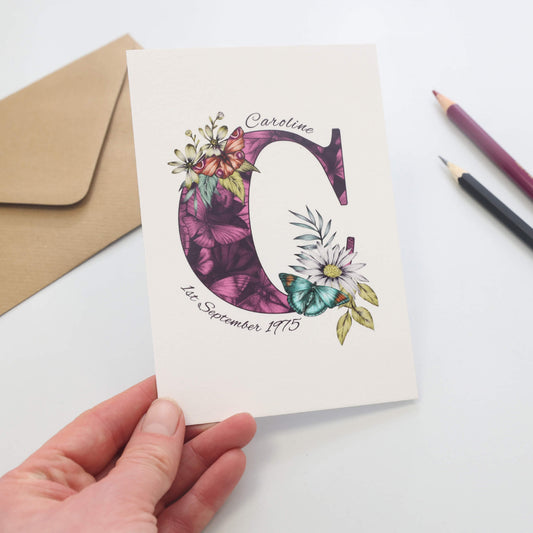 Purple butterfly themed personalised ‘C’ initial birthday card, initial filled with hand-drawn butterflies and flowers. The recipients name and date of birth is incorporated into the design.