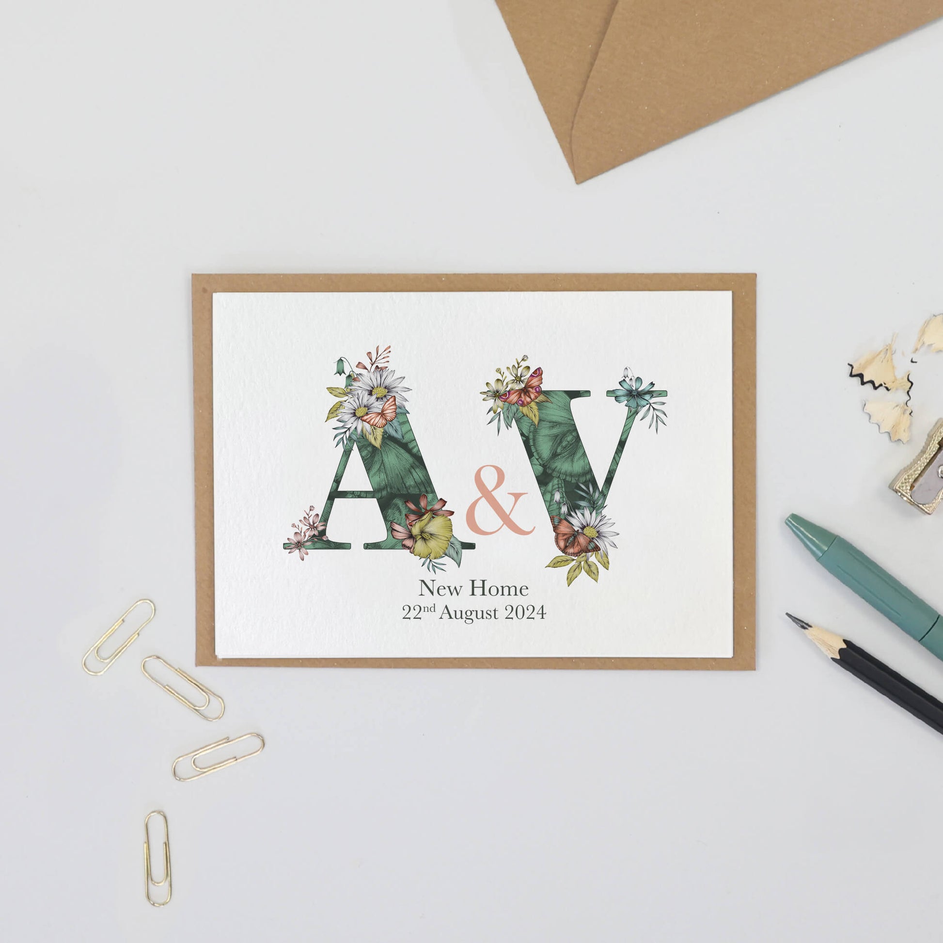 Green butterfly themed personalised initial new home card with a & v initials filled with hand-drawn butterflies and flowers. The wording ‘new home’ and date is printed underneath initials.