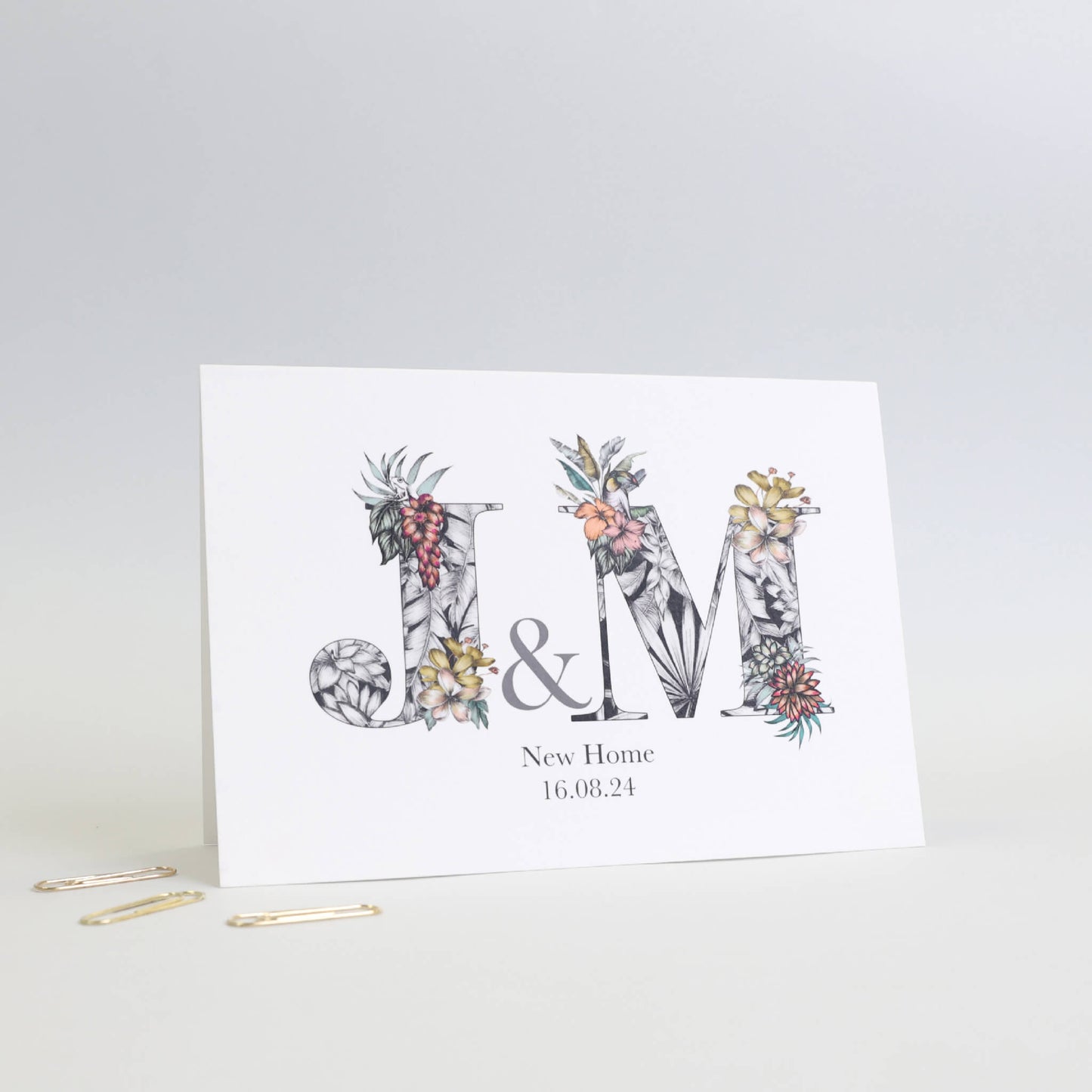 personalised j and m initials new home card with with hand-drawn tropical imagery. New home and the couple's moving in date is printed underneath