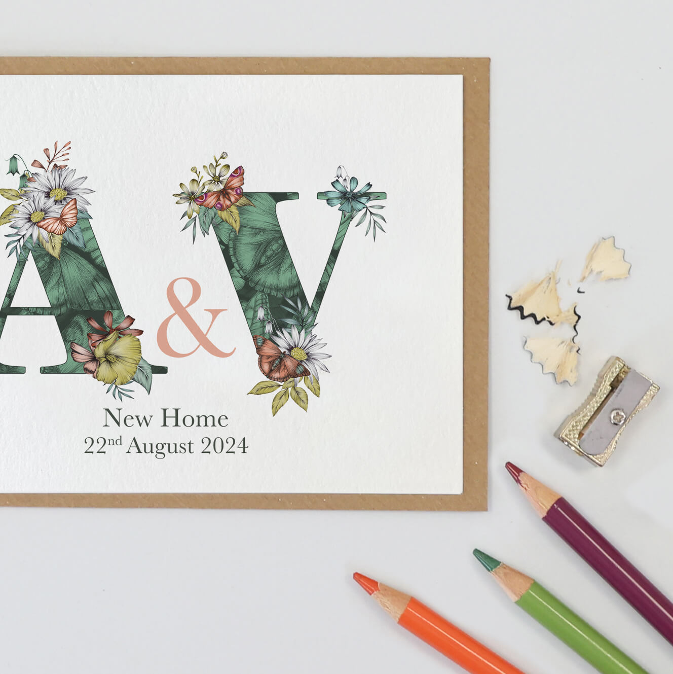 Green butterfly themed personalised initial new home card with a & v initials filled with hand-drawn butterflies and flowers. The wording ‘new home’ and date is printed underneath initials.