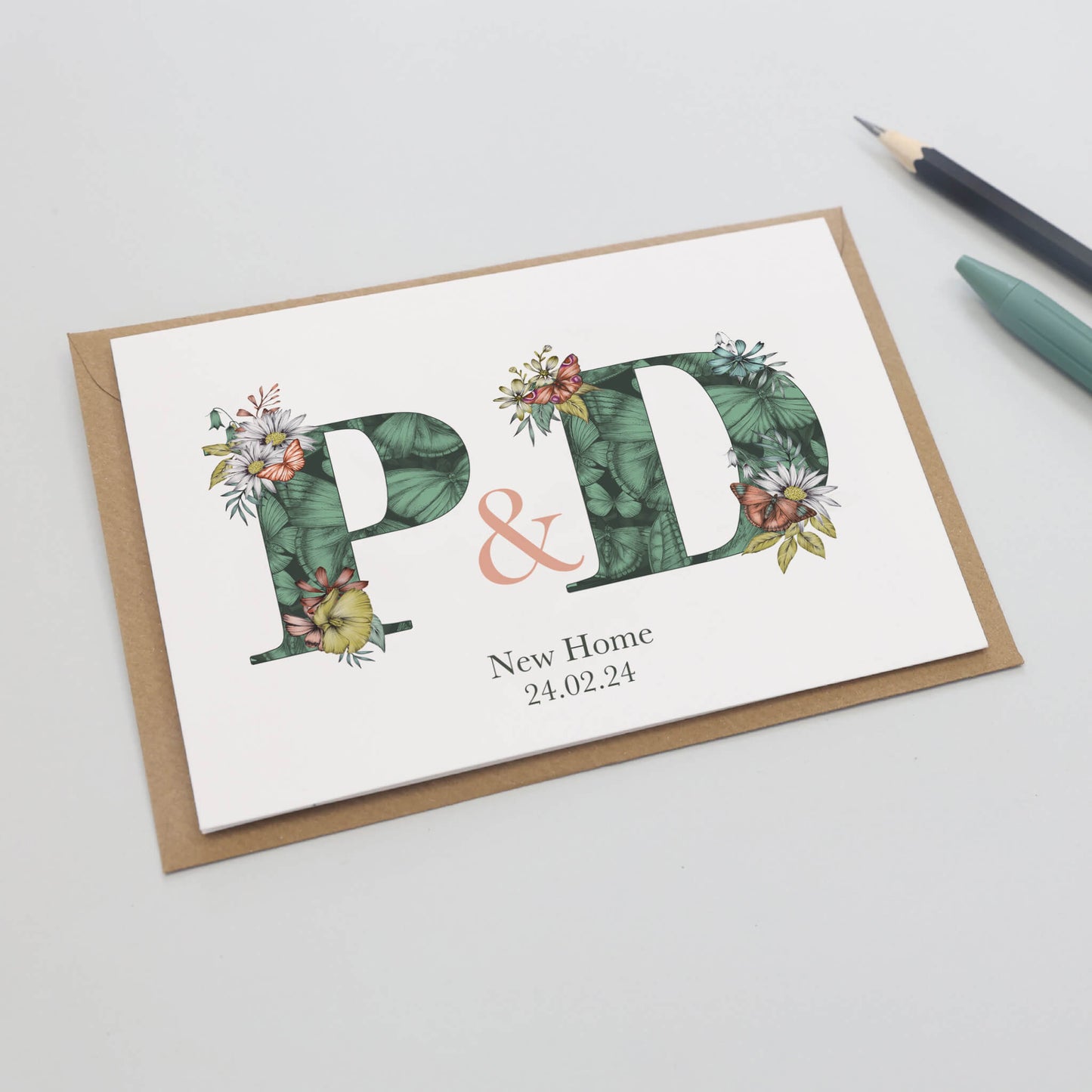 Green butterfly themed personalised initial new home card with p & d initials filled with hand-drawn butterflies and flowers. The wording ‘new home’ and date is printed underneath initials.