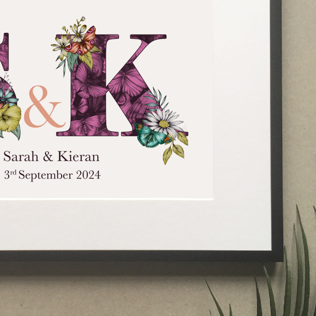 Close up of personalised initial digital print of S & K. Initials are filled with purple fine liner drawings of butterflies and flowers. Under initials ’Sarah and Kieran are printed and under that their wedding date ‘3rd September 2024 is also printed.